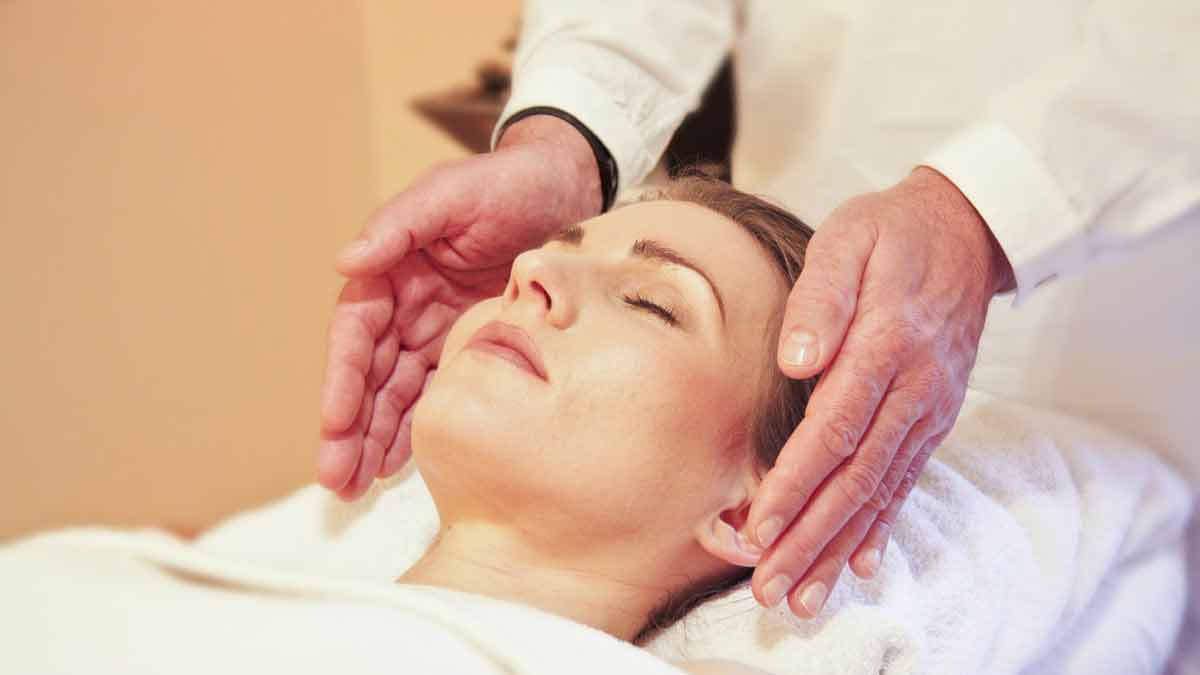 What is Reiki? - woman with her eyes closed receiving Reiki on the sides of her head