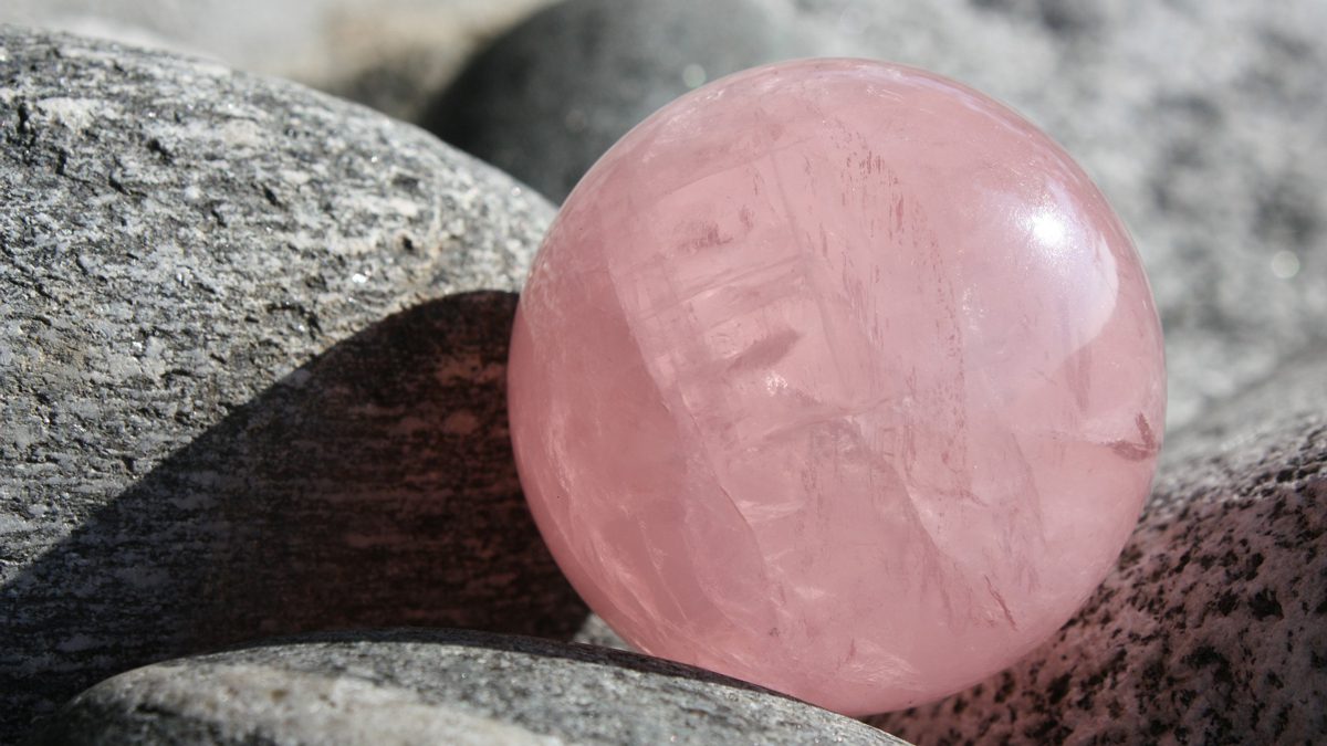 Jerry Mikutis - Chicago Reiki and Crystals: Rose Quartz - Image of rose quartz sphere resting amid rocks